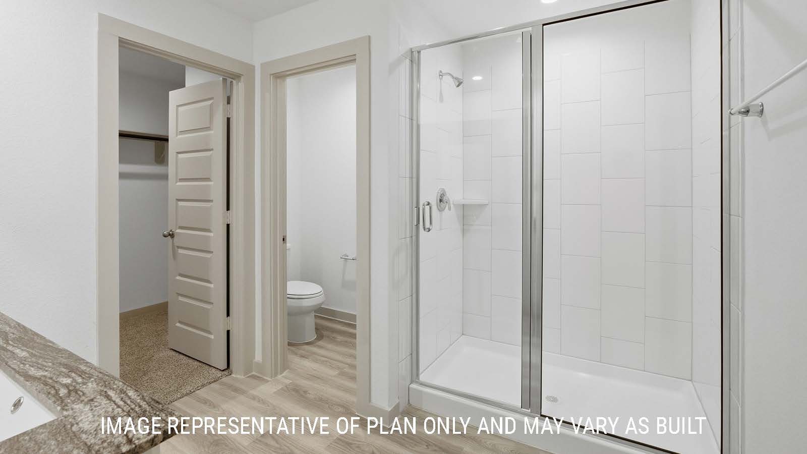 Bellvue primary bathroom with walk-in shower and view of primary bedroom walk-in closet.