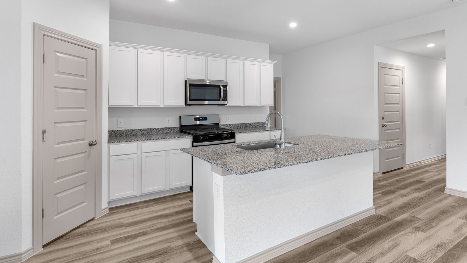 Camden kitchen island with granite countertops and view of secondary bedroom.