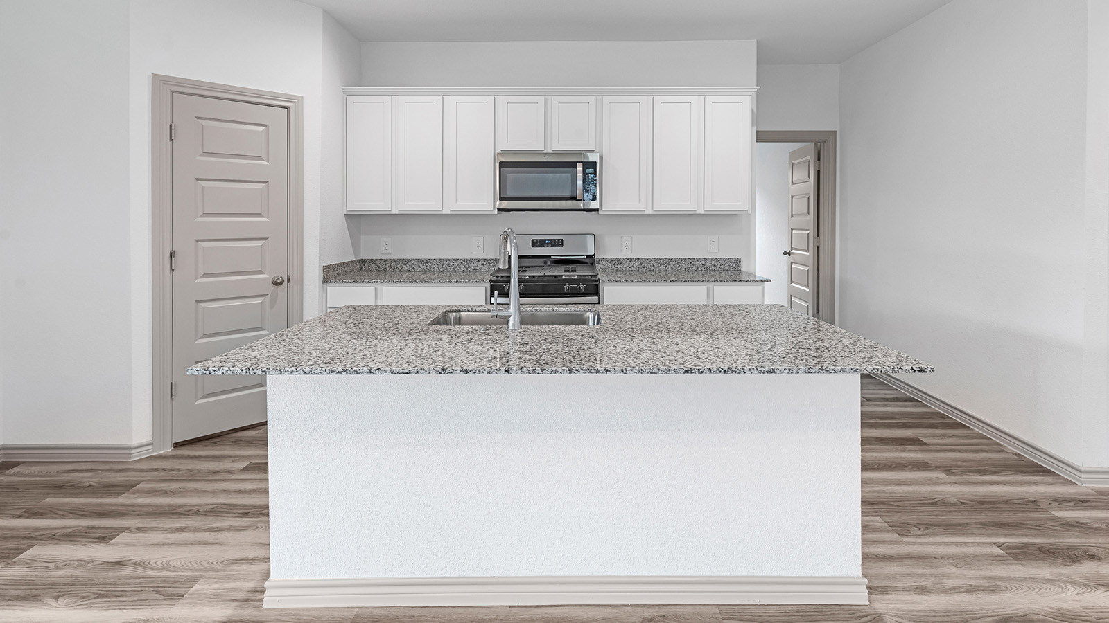 Camden kitchen island with granite countertops and view of secondary bedroom.