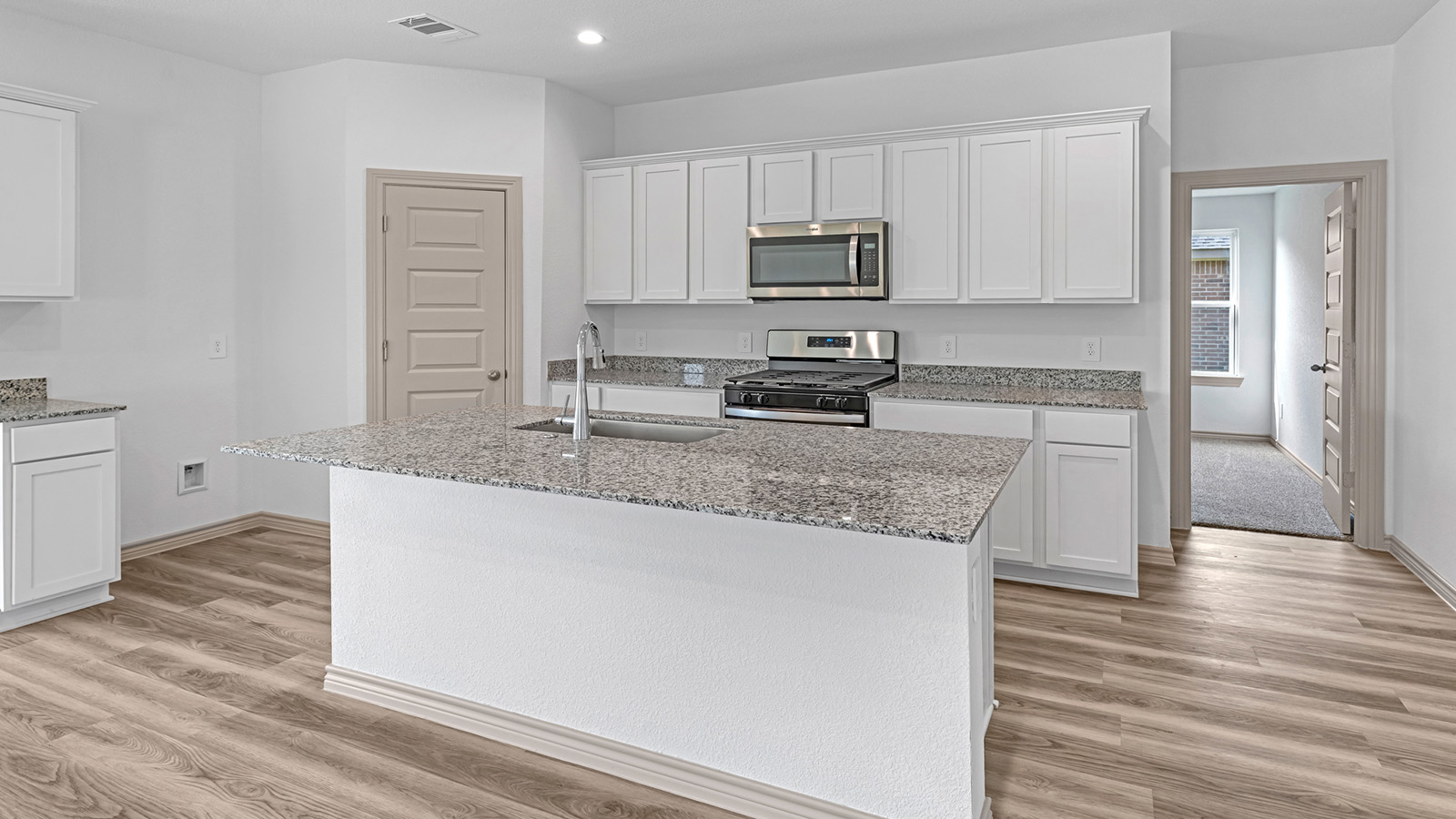 Camden kitchen island with granite countertops and view of hallway.