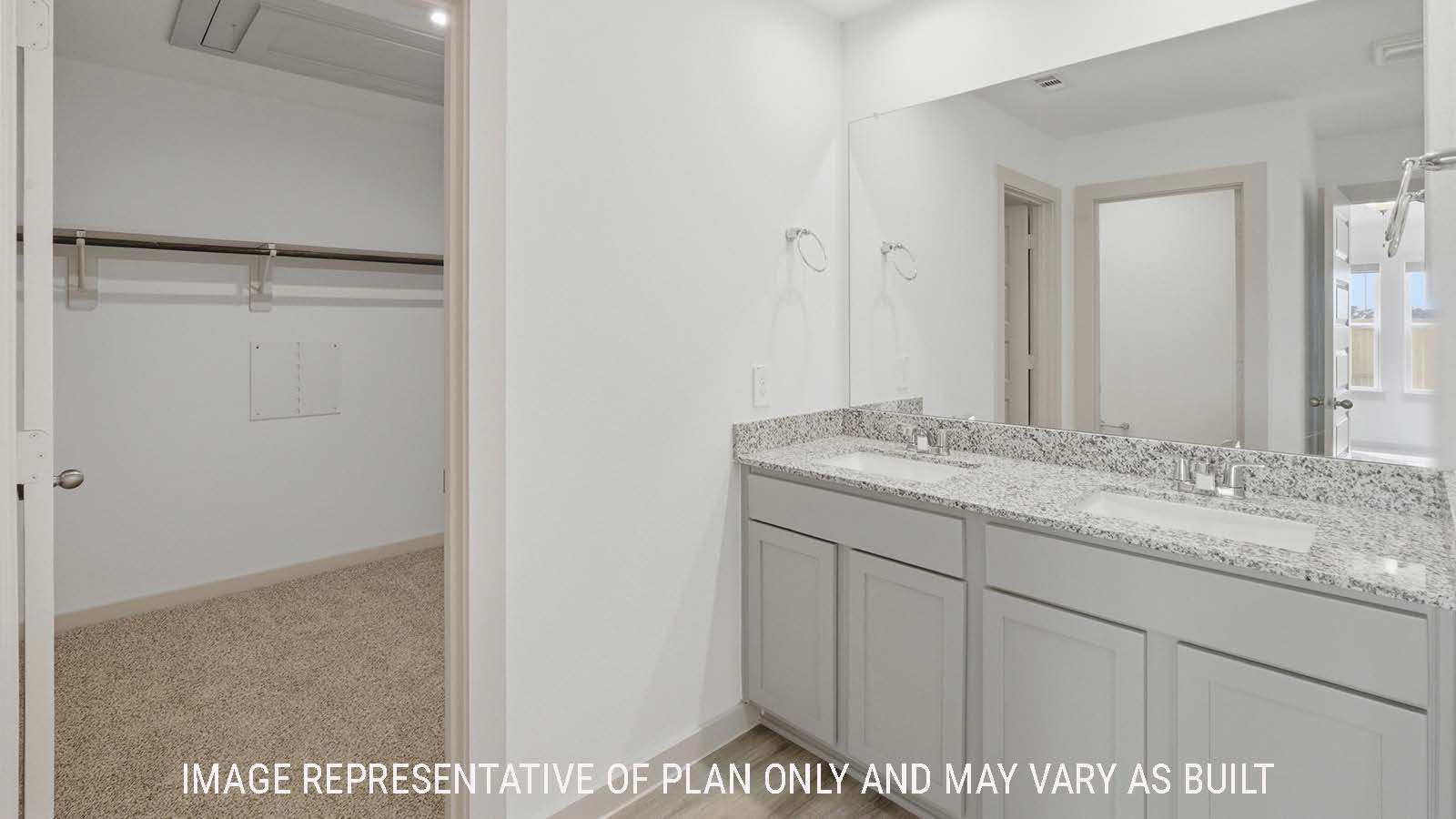 Texas Cali primary bathroom with double vanity sink with granite countertops and view of primary bedroom closet.