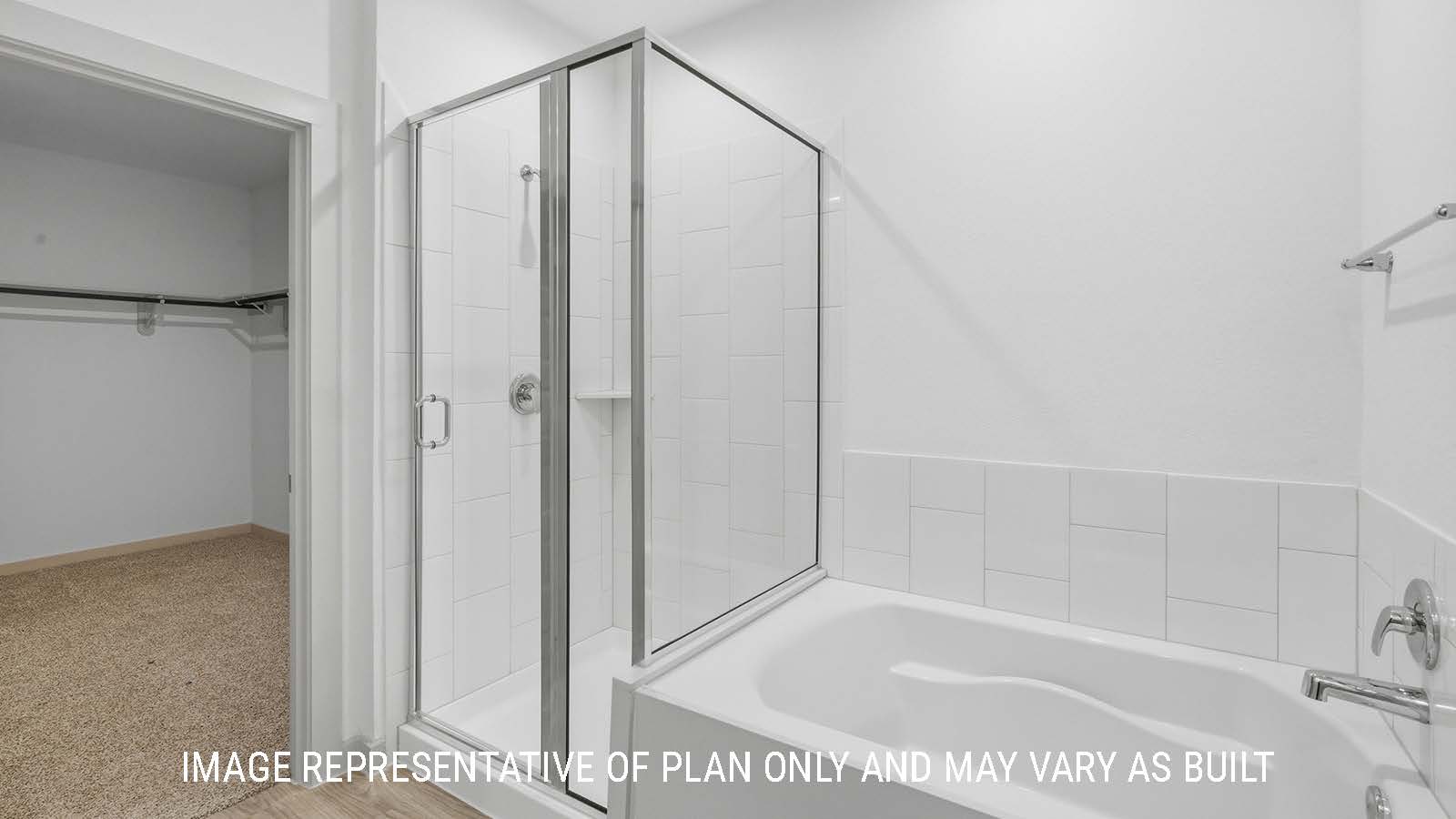 Mitchell primary bathroom with garden tub and walk-in shower and view of primary bedroom walk-in closet.