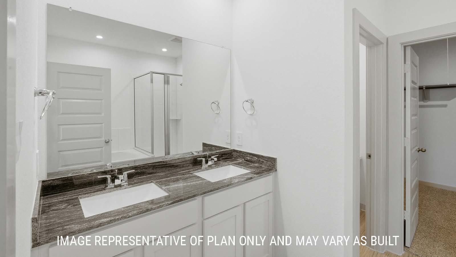 Mitchell primary bathroom with double vanity sink and view of primary bedroom walk-in closet.