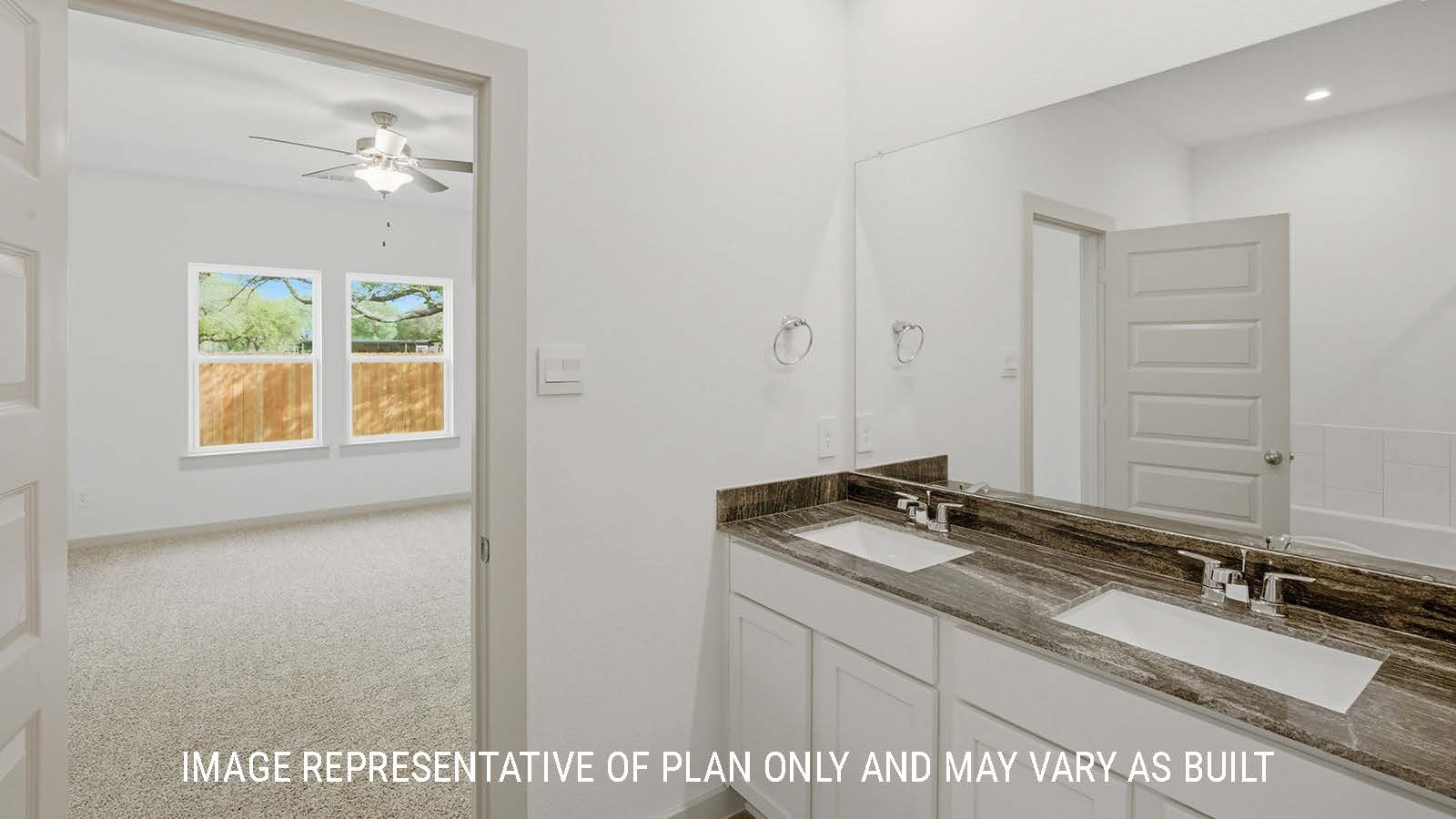 Mitchell primary bathroom with double vanity sink and view of primary bedroom.