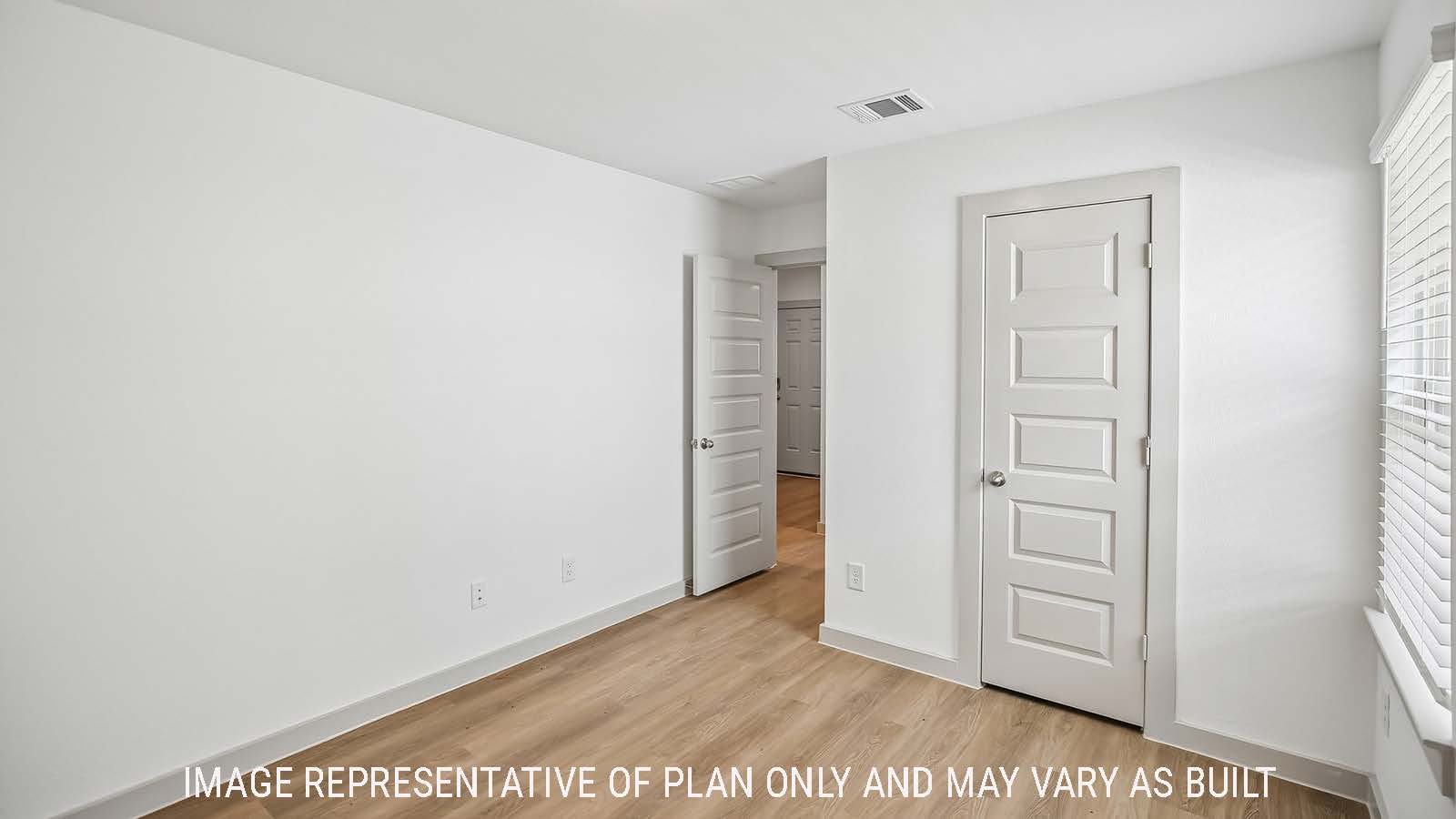 Denton secondary bedroom with vinyl plank flooring and view of hallway.