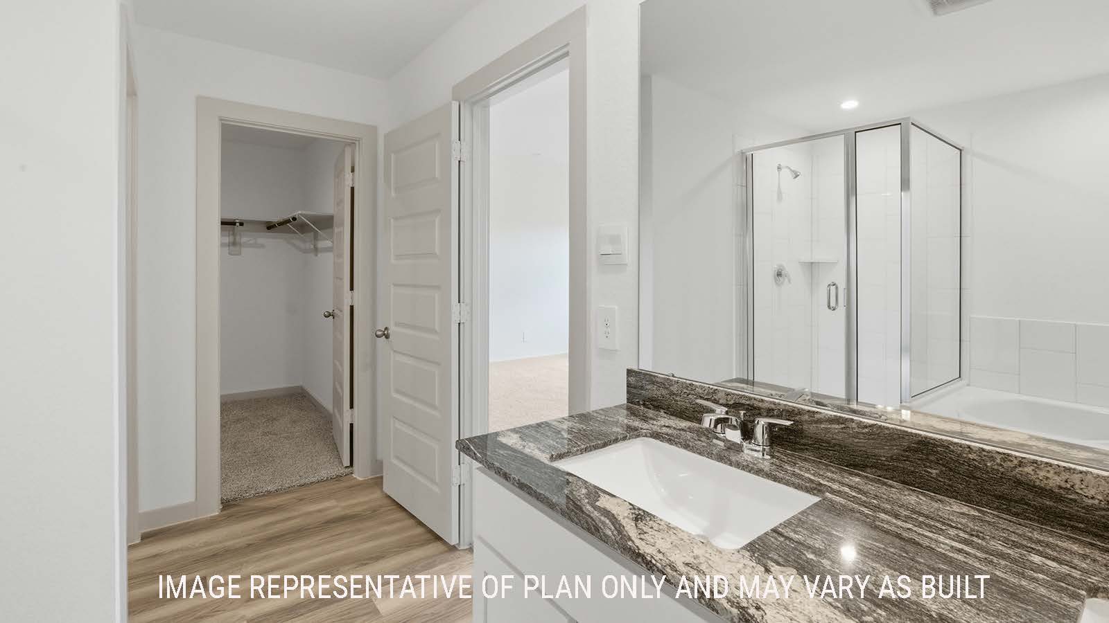 Kingston primary bathroom with double vanity sink and view of primary bedroom walk-in closet.
