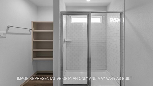 Cali primary bathroom with walk-in shower and shelving for storage.