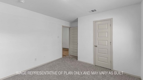 Cali secondary bedroom with carpet flooring and view of the hallway.