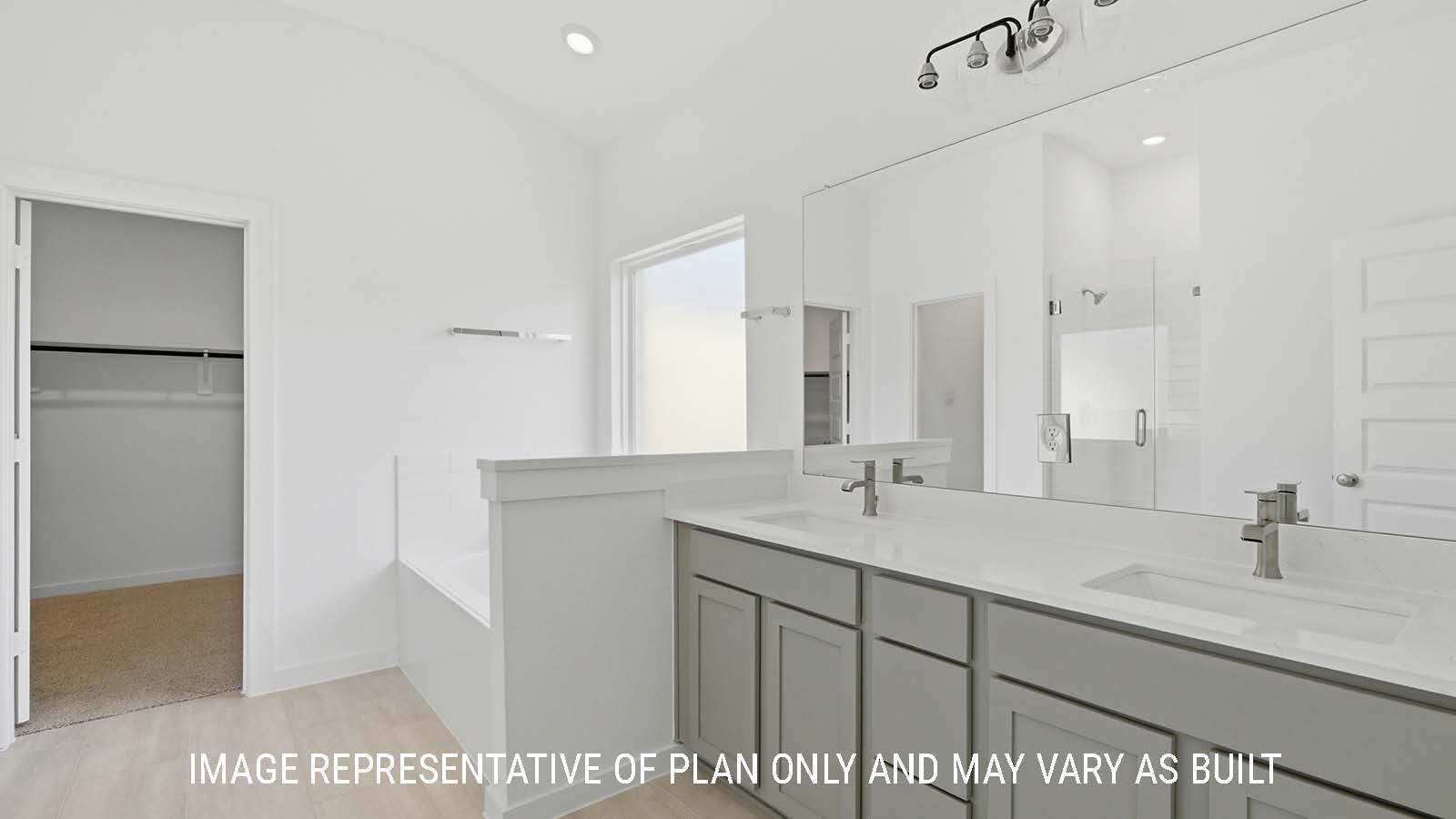 Waverley primary bathroom with double vanity sink and garden tub and view of walk-in closet.