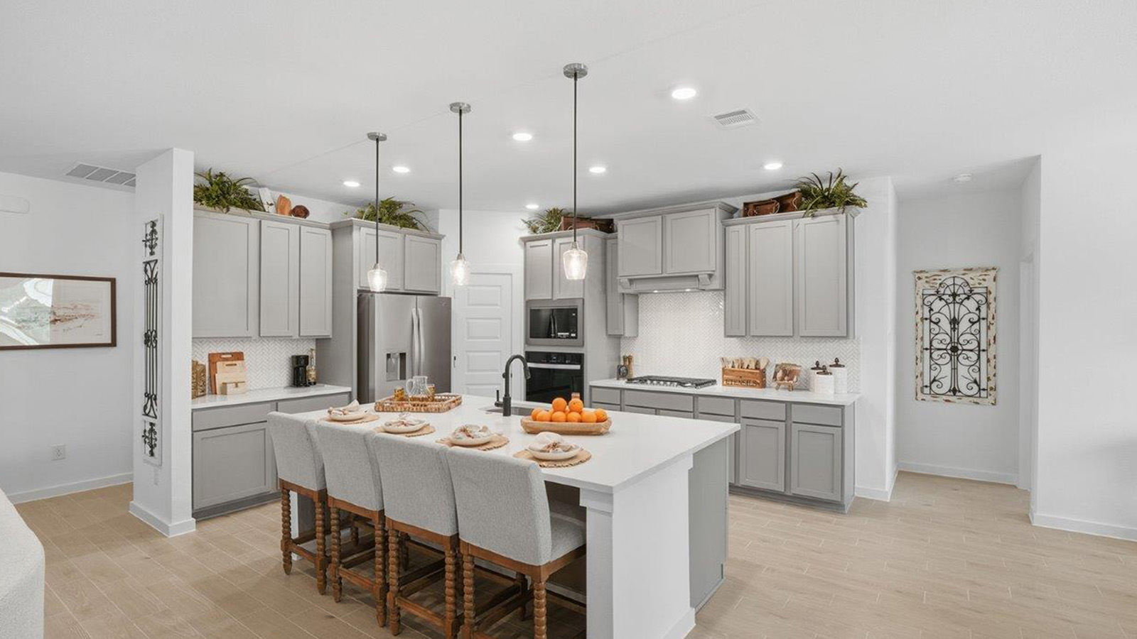 The woods model home kitchen with kitchen island with grey cabinets and light granite countertops.