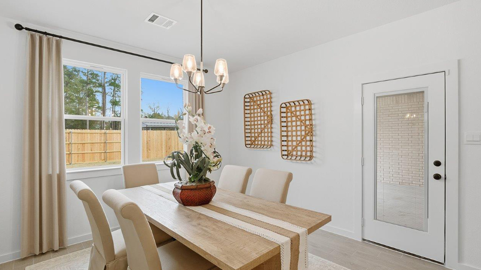 The woods model home dining room with dining room table and view of back door and back yard.
