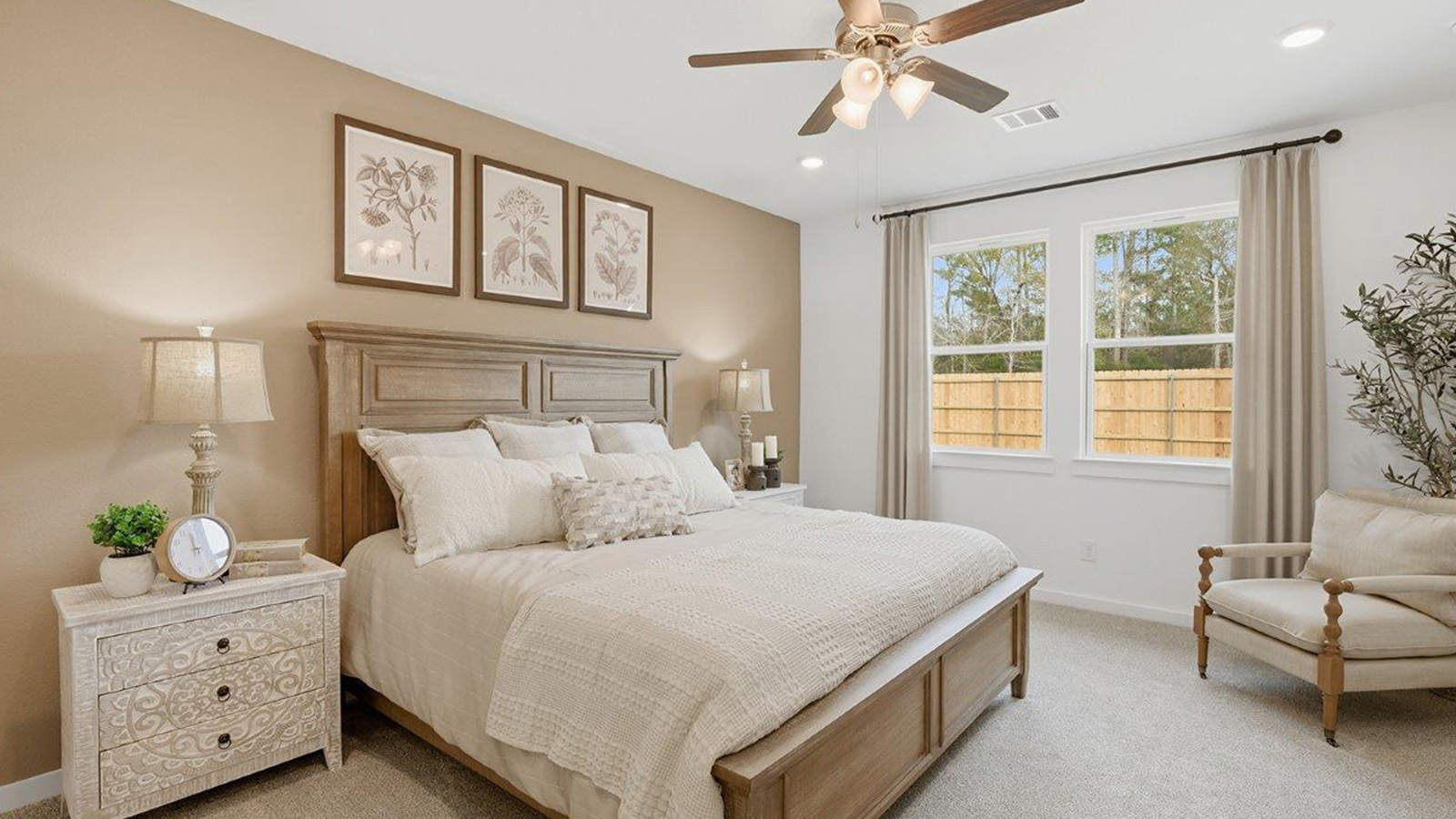 The woods model home primary bedroom with carpeted flooring and windows for natural lighting.