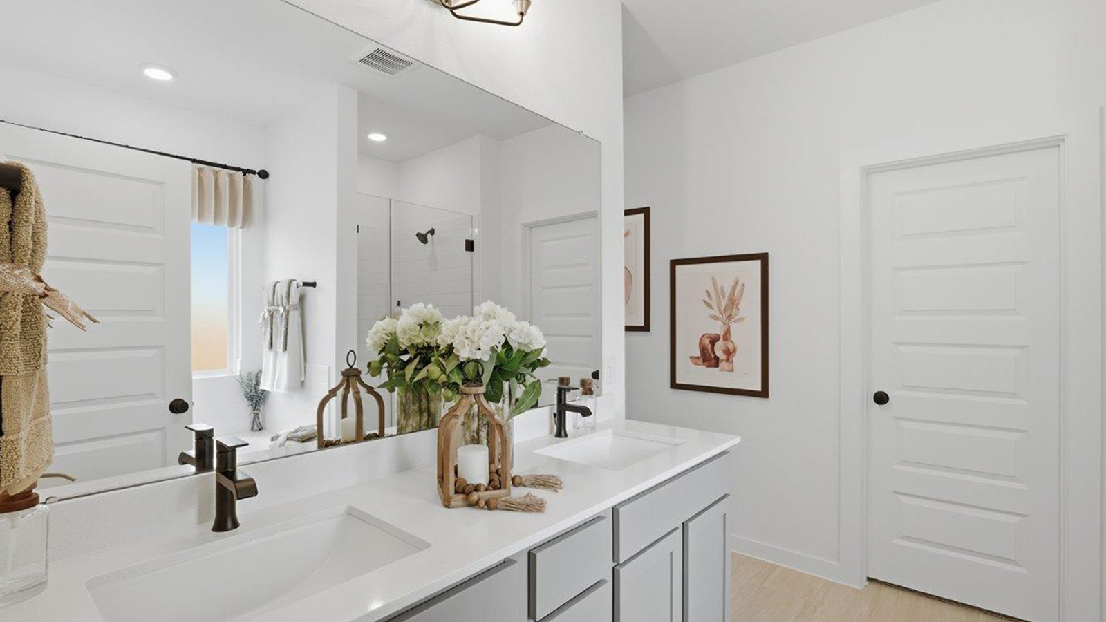 The woods model home primary bathroom with duel vanity sinks and mirror.