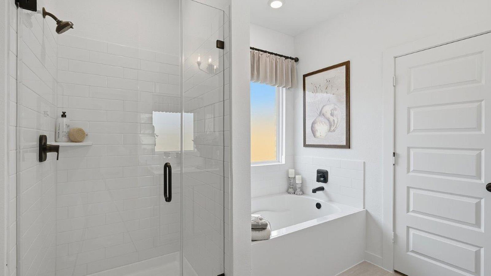 The woods model home primary bathroom with walk-in shower and garden tub.