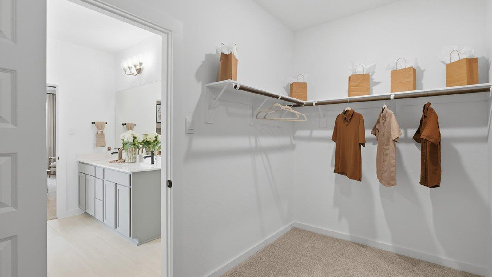 The woods model home primary bedroom walk-in closet with carpeted flooring and shelving for storage.