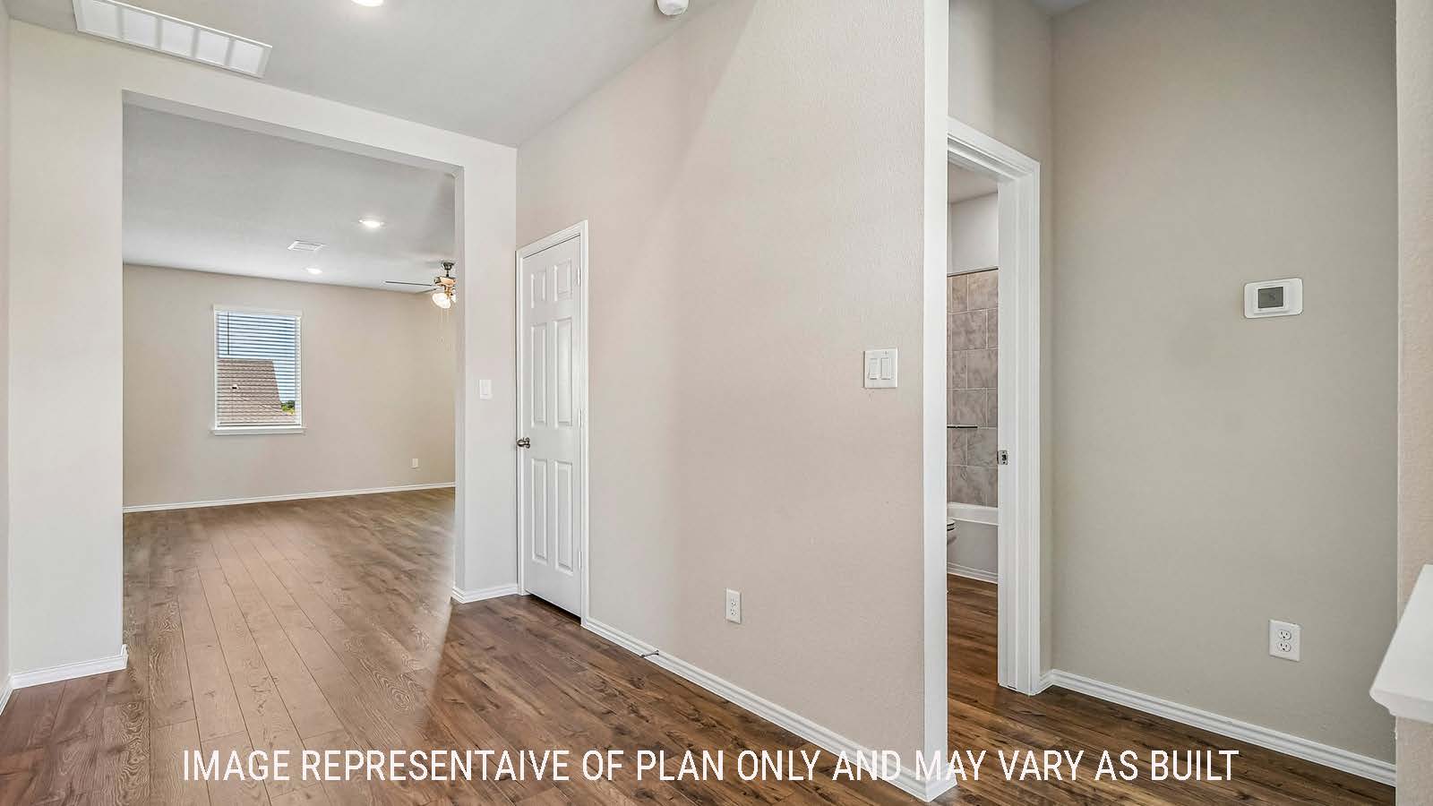 Prosper hallway with view of secondary bathroom and view of open concept living room.