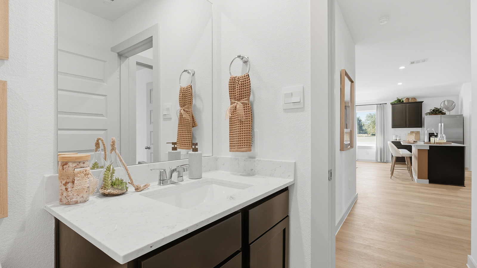 Highland Village model home secondary bathroom with vanity sink and view of living room.