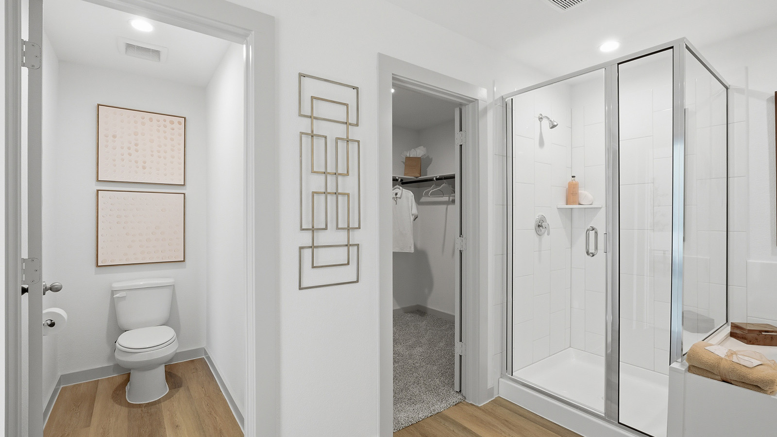 Highland Village model home primary bathroom with walk-in shower and view of primary walk-in closet.