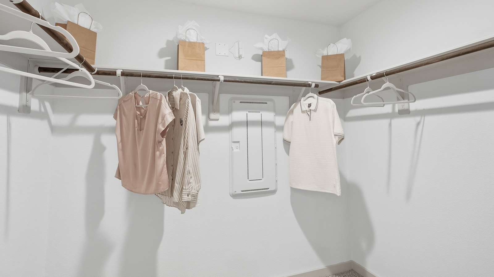 Highland Village model home primary bedroom walk-in closet with carpeted flooring and shelving for storage.