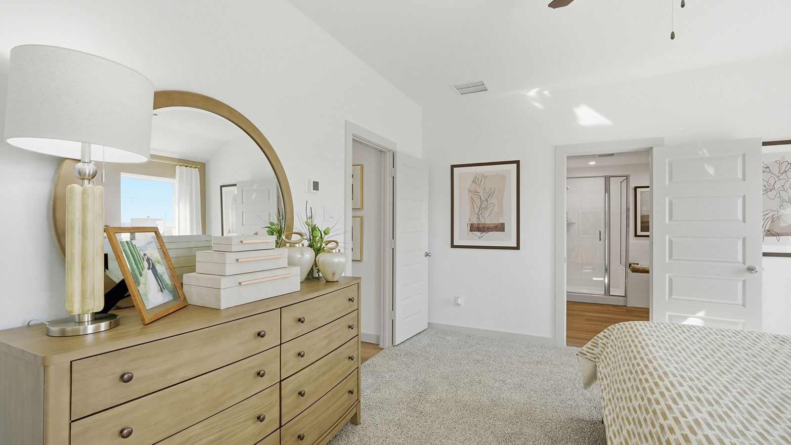 Highland Village model home primary bedroom with carpeted flooring and view of primary bathroom.
