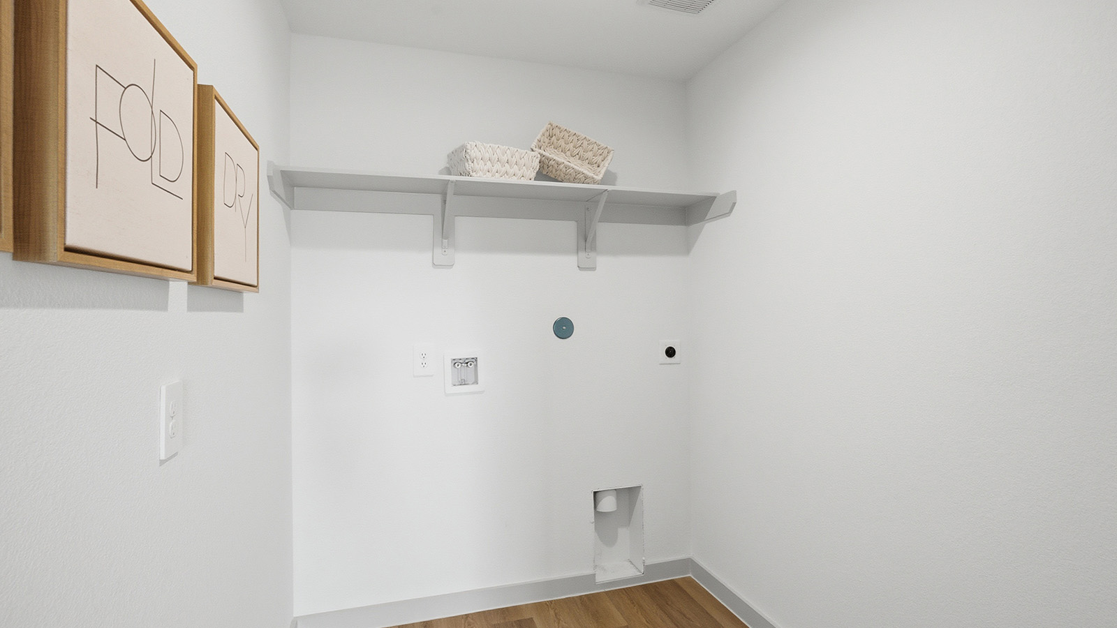 Highland Village model home utility room with washer and dryer connections and shelving for storage.