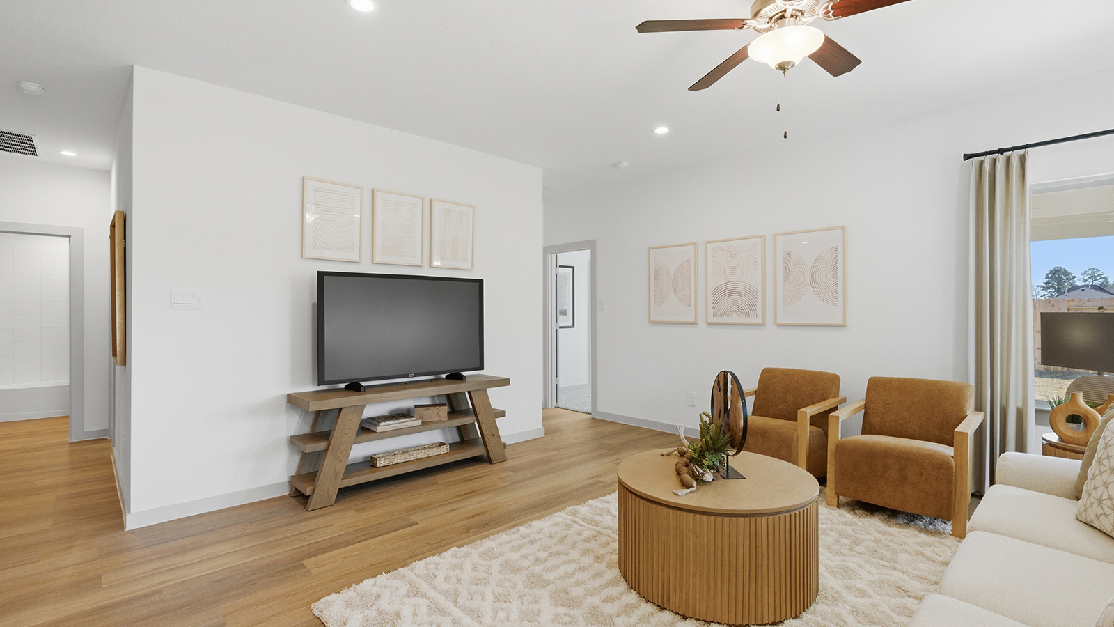 Highland Village model home living room with view of hallway to secondary and primary bedrooms.