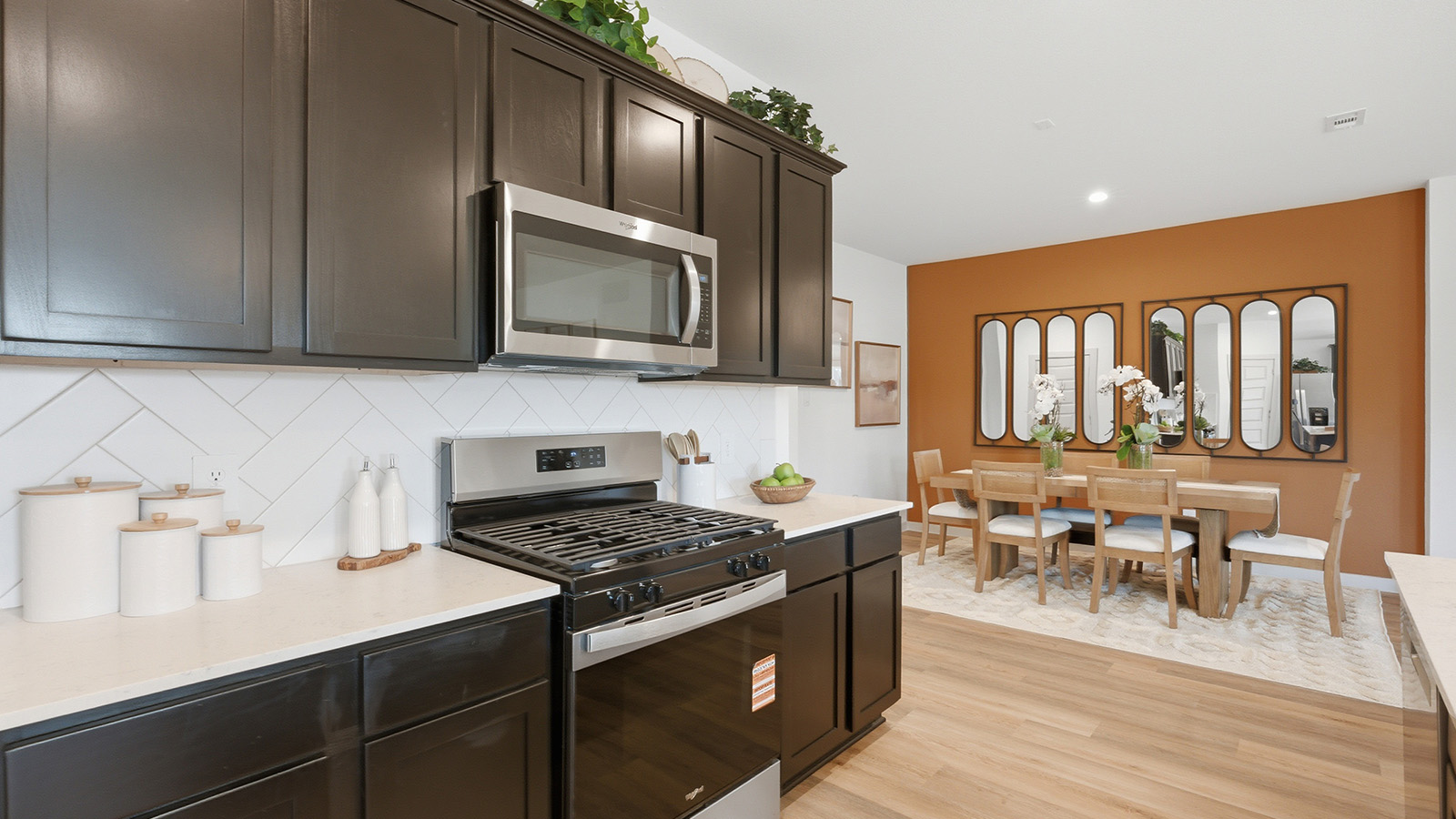 Highland Village model home kitchen with dark cabinets and light countertops and view of dining room.