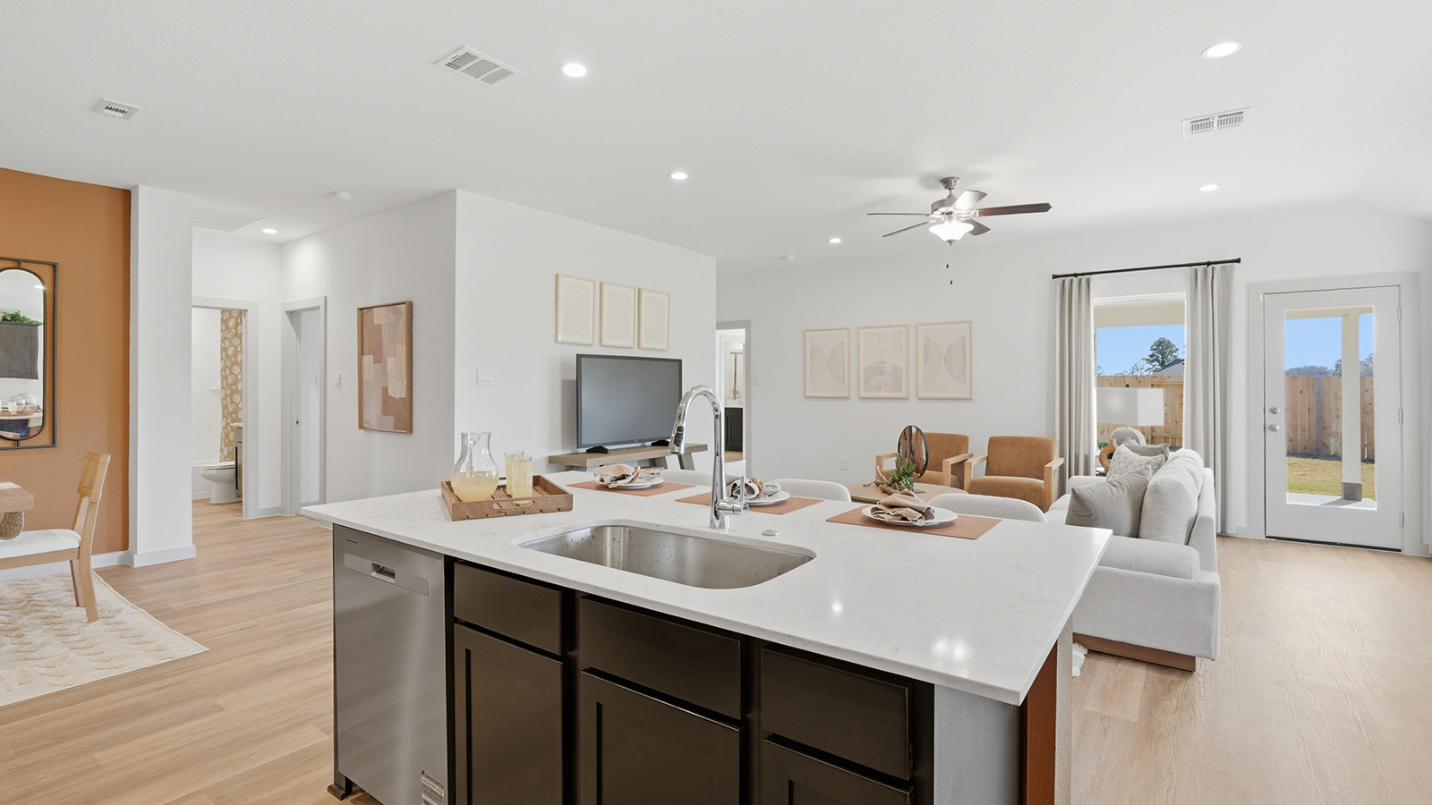 Highland Village model home kitchen with kitchen island with light countertops with view of living room.