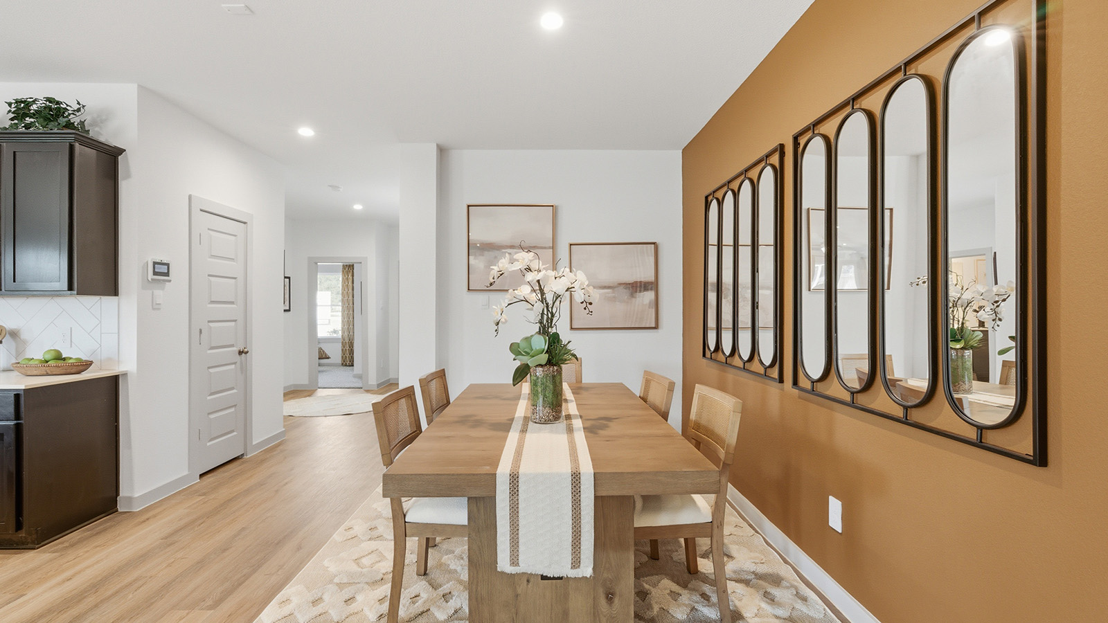 Highland Village model home dining room with view of kitchen and front entry way.