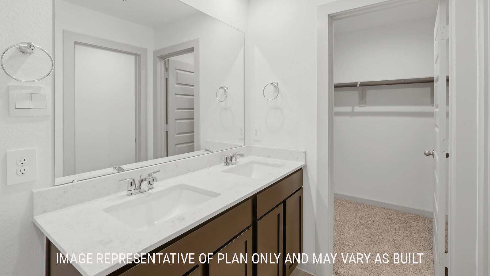 Elgin primary bathroom with dual vanity sink and view of primary bedroom walk-in closet.