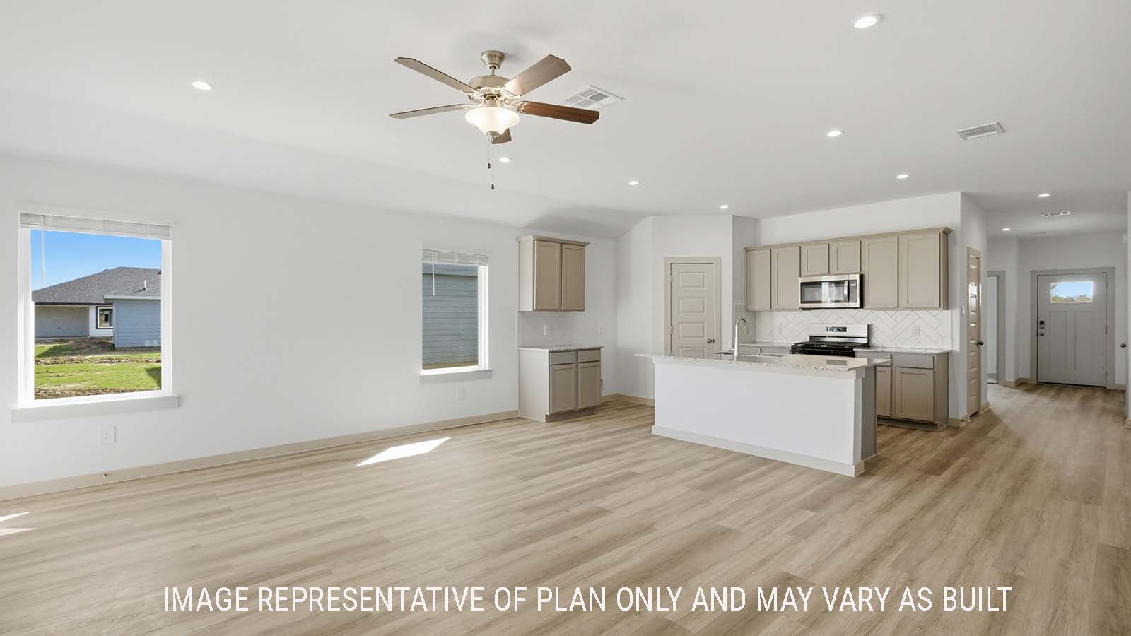 Lakeway living room with vinyl plank flooring and view of open concept kitchen and front entry hallway.