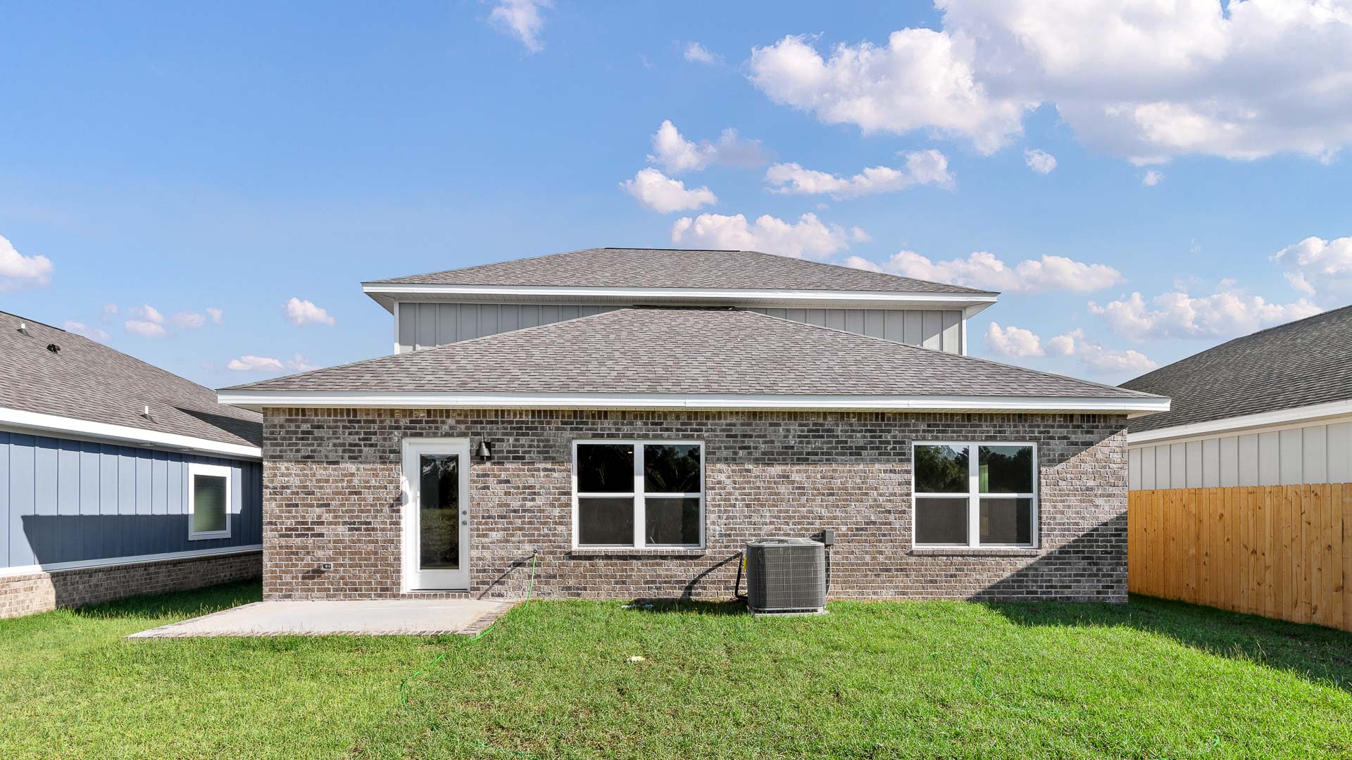 The back of the home has brick on the main level and a patio
