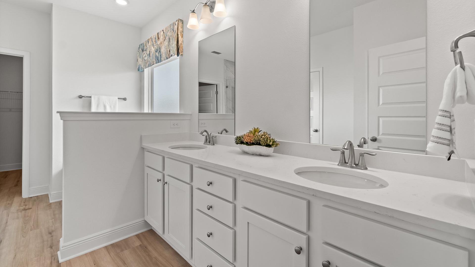 The primary bathroom features a dual sink vanity with lower cabinetry and drawers for storage