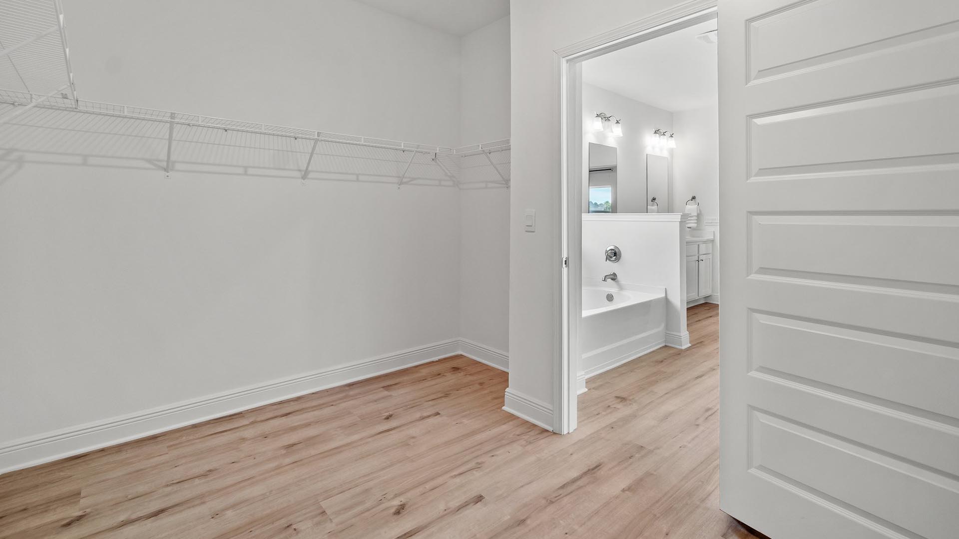 The closet in the primary bedroom is spacious and features upper ventilated shelving
