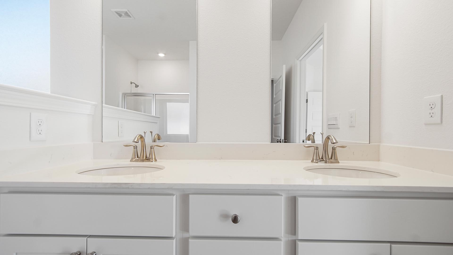 The primary bathroom has a dual sink vanity with quartz countertops and lower cabinetry for storage
