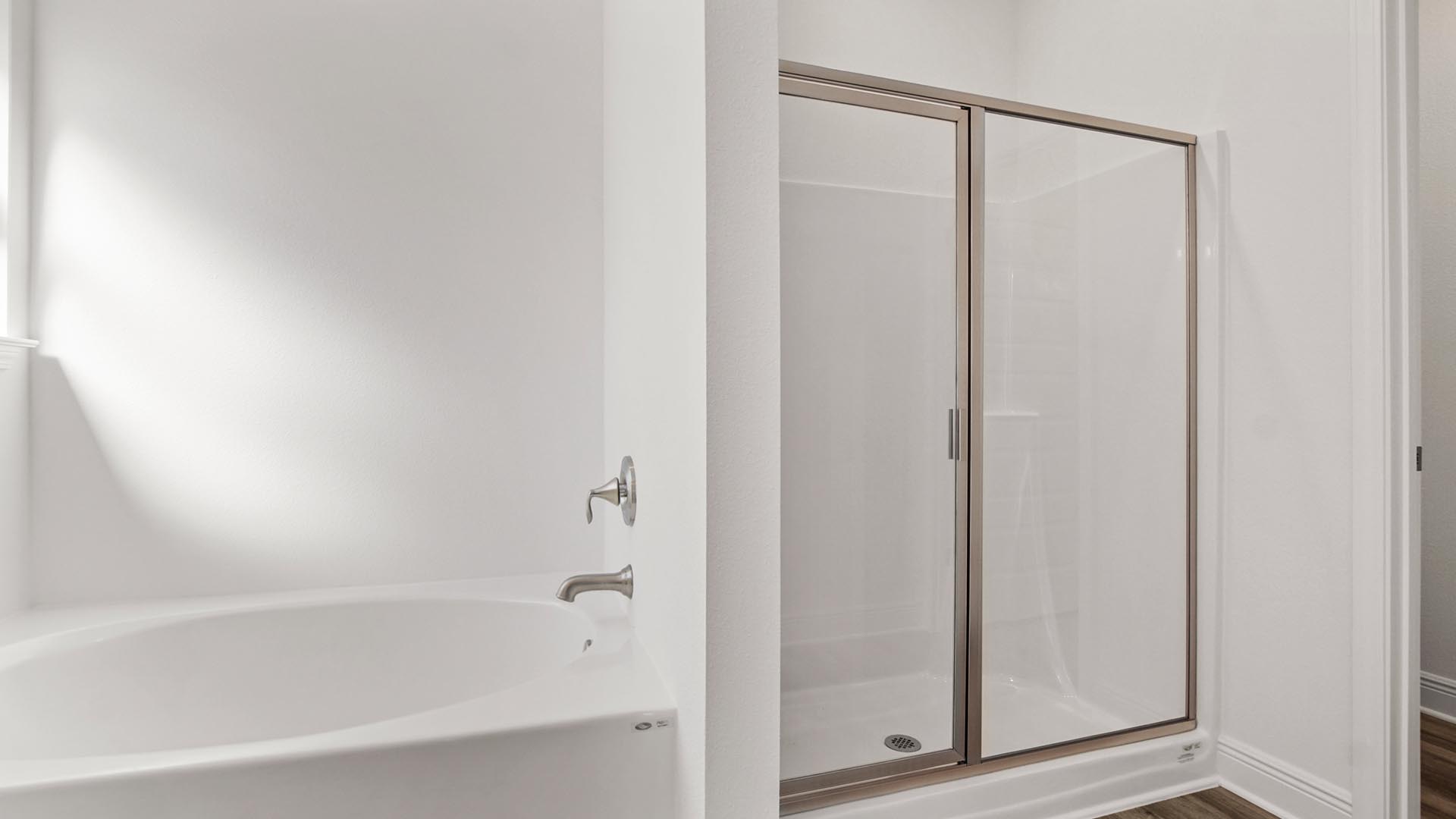 There is a separate shower with glass enclosure in the primary bathroom