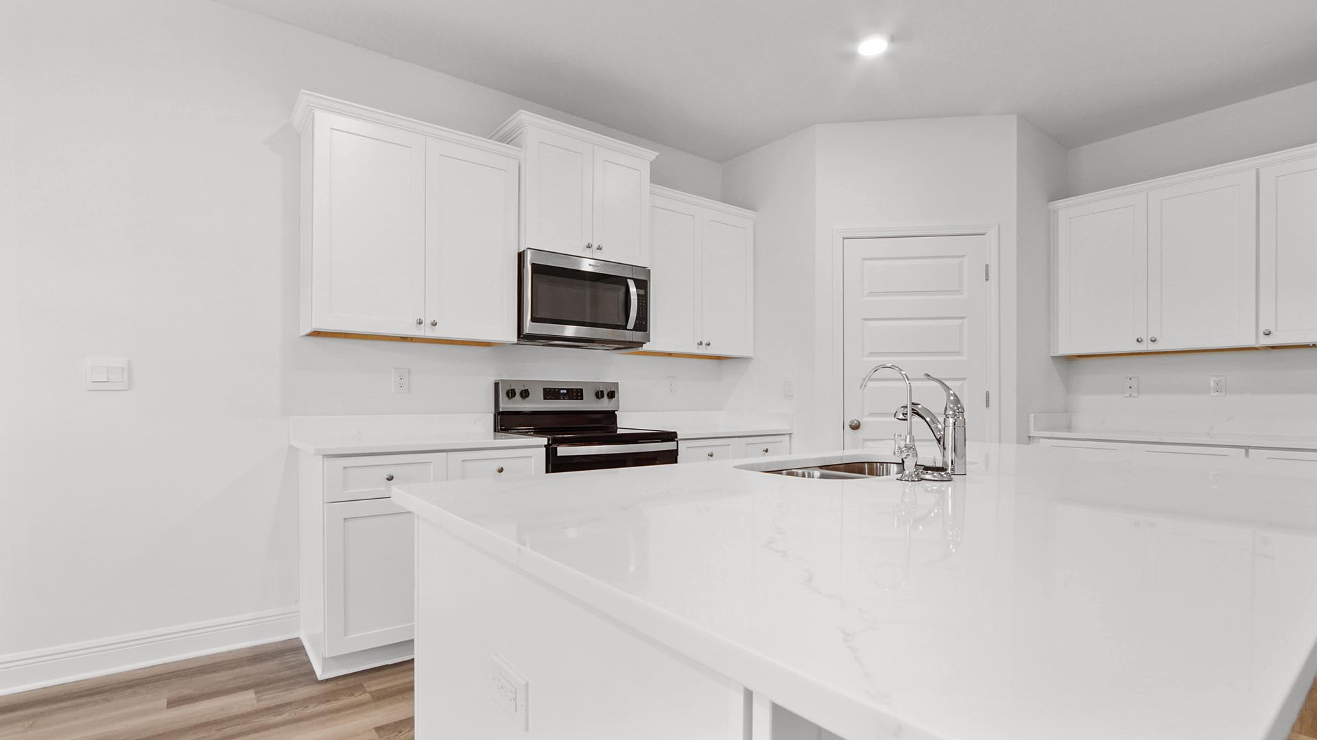 Kitchen with corner walk in pantry and stainless steel appliances and undermount sink in island.
