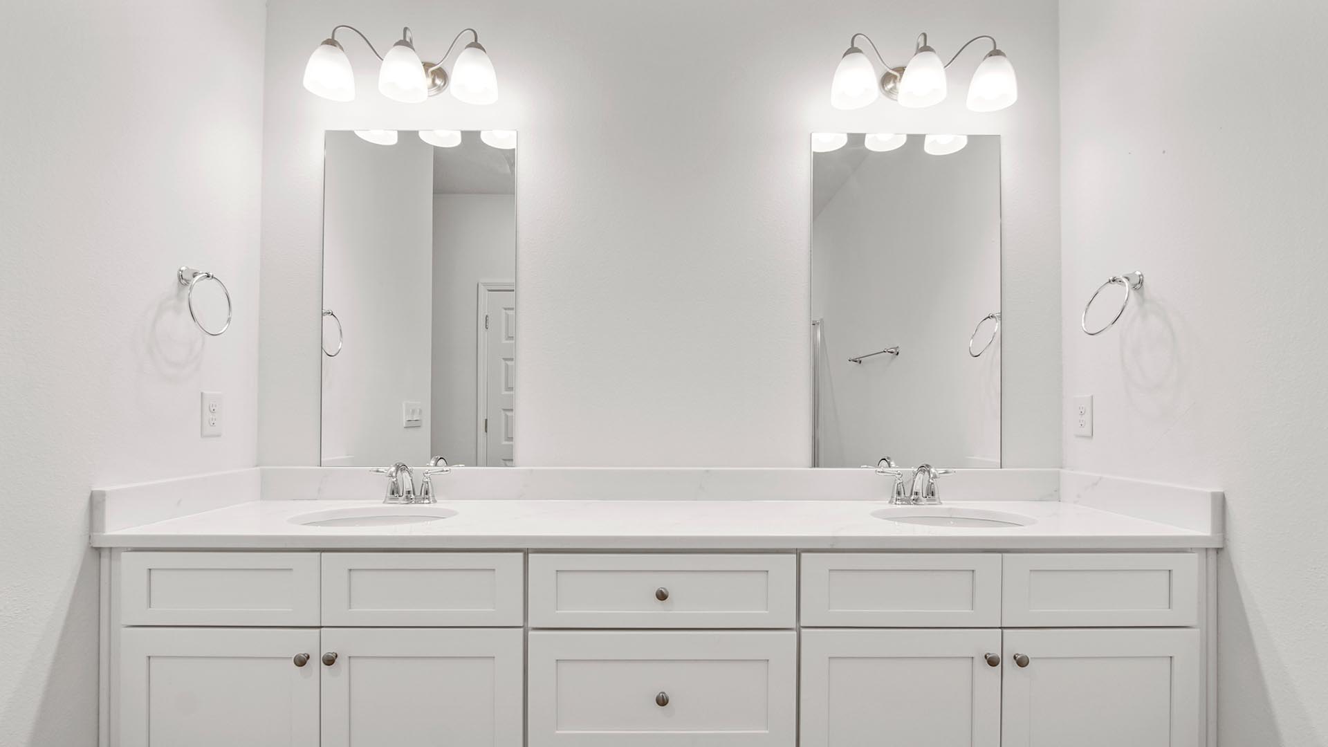 Primary bathroom with double vanity with white cabinetry and quartz countertops.