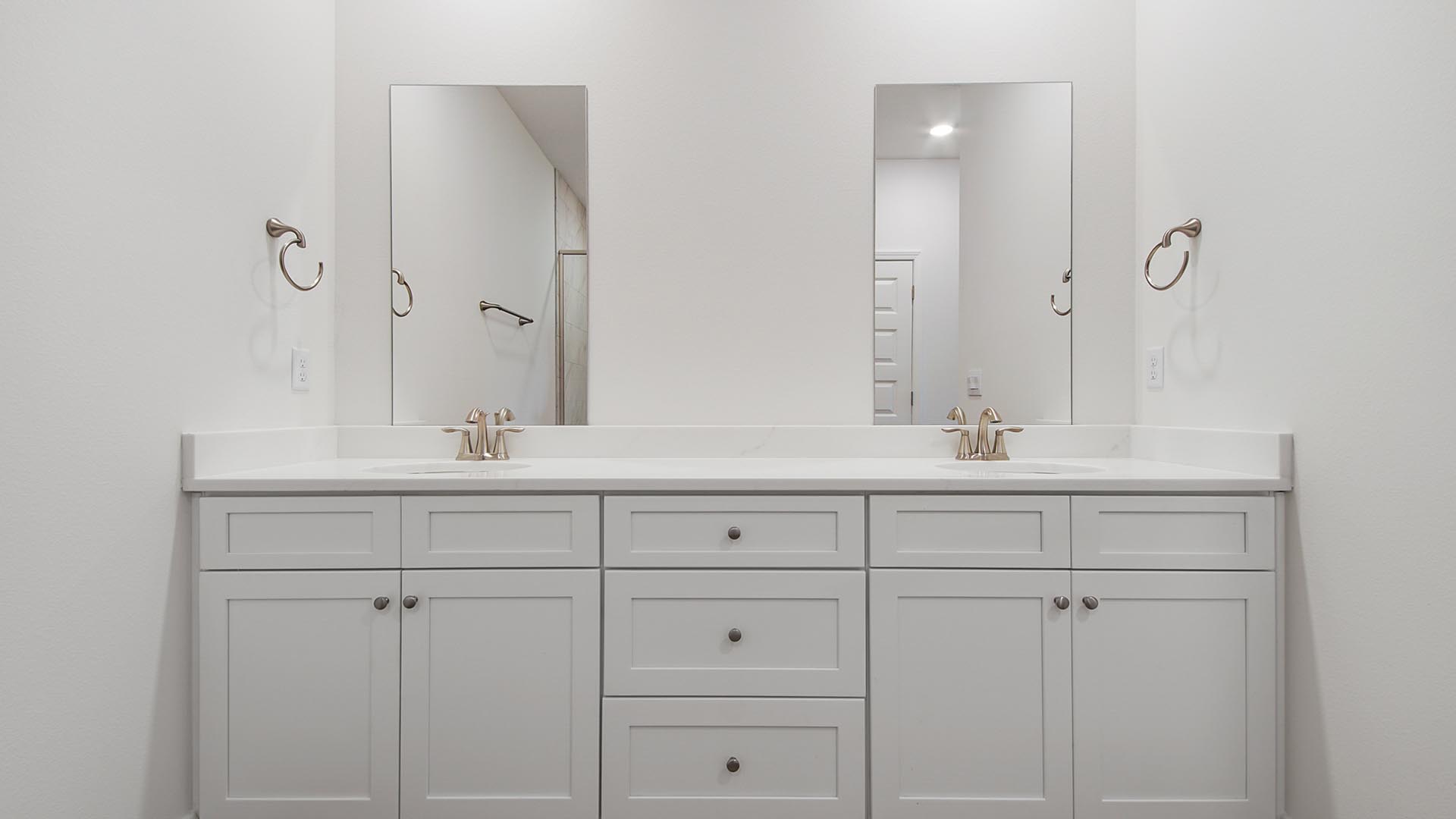 The primary bathroom features a dual sink vanity with lower cabinetry and quartz countertops