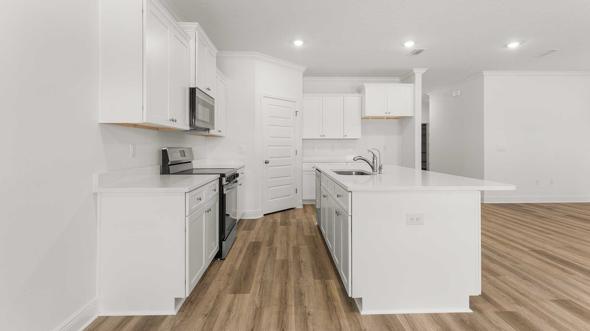 The kitchen has been elegantly appointed with white cabinetry and quartz countertops
