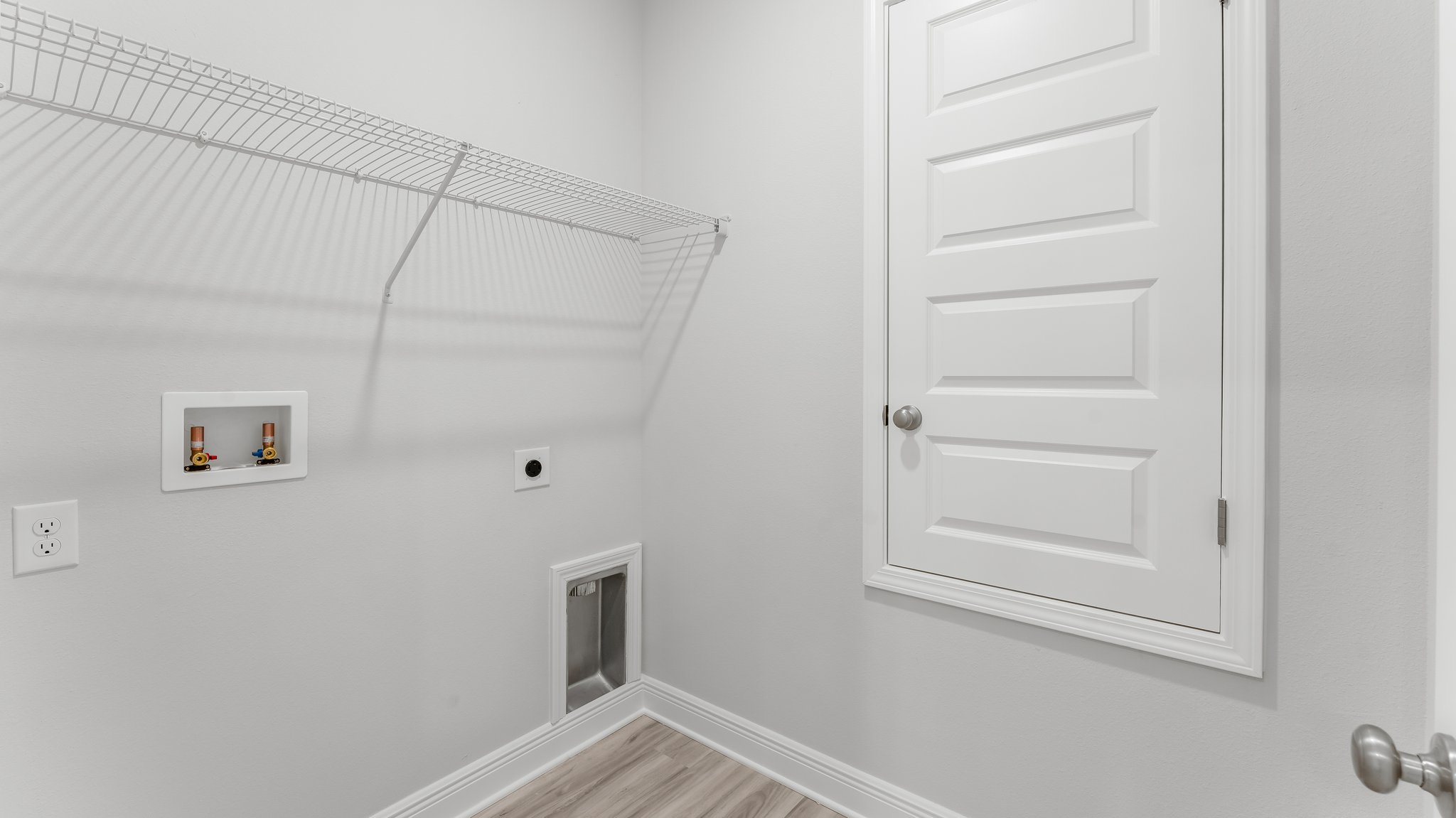 There is a laundry room with washer dryer hookups and overhead ventilated shelving