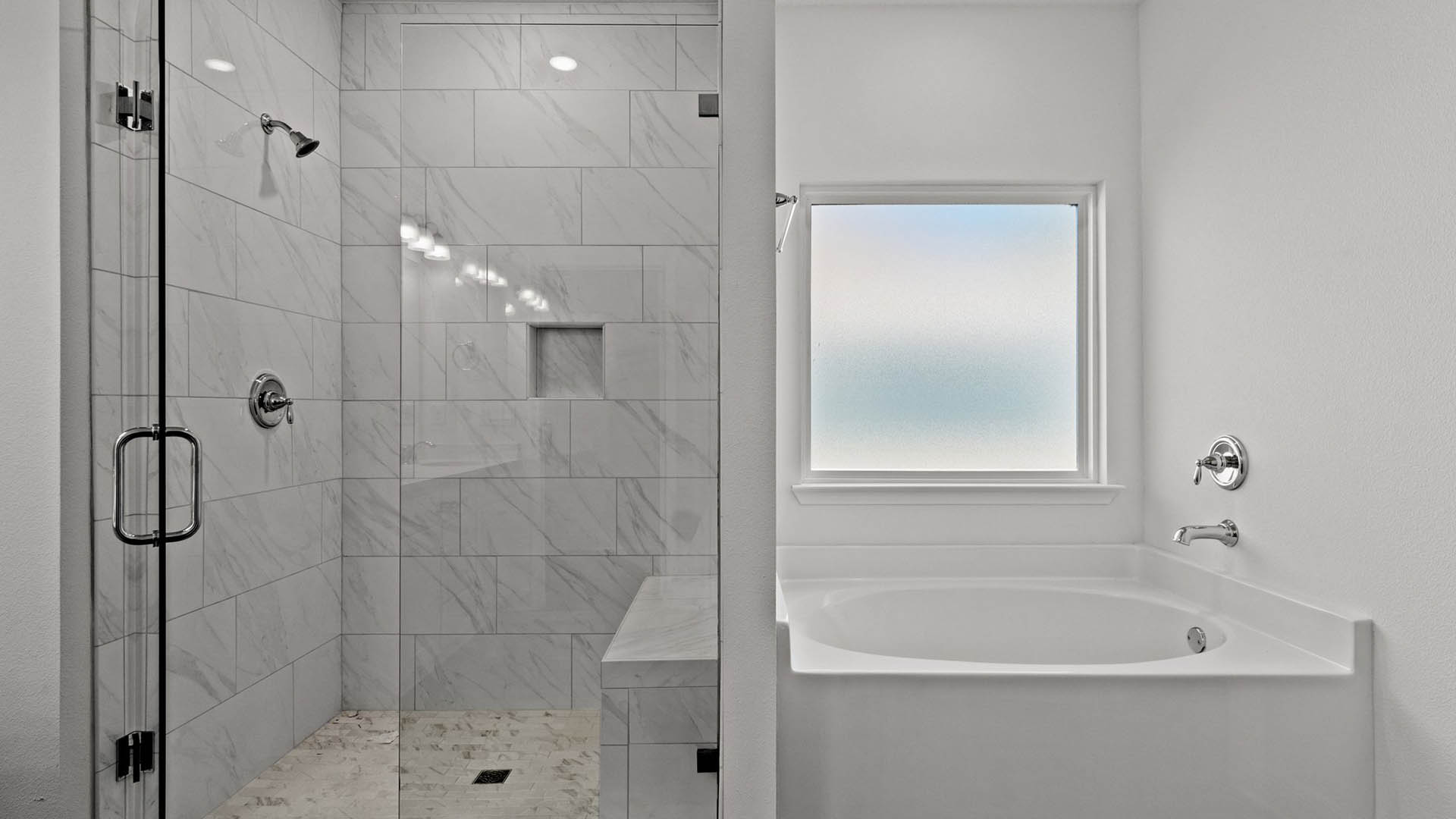 Primary bathroom has an elegant tile shower with glass enclosure and large soak tub