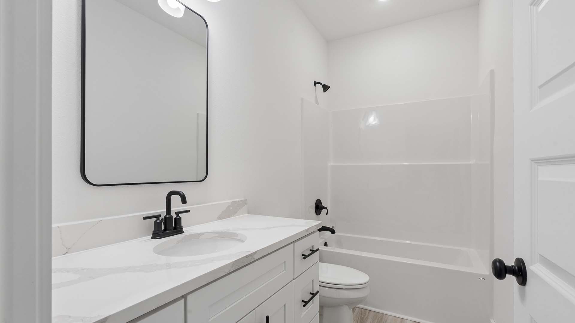 The shared bathroom has a shower tub combination and a single vanity with lower cabinetry for storage