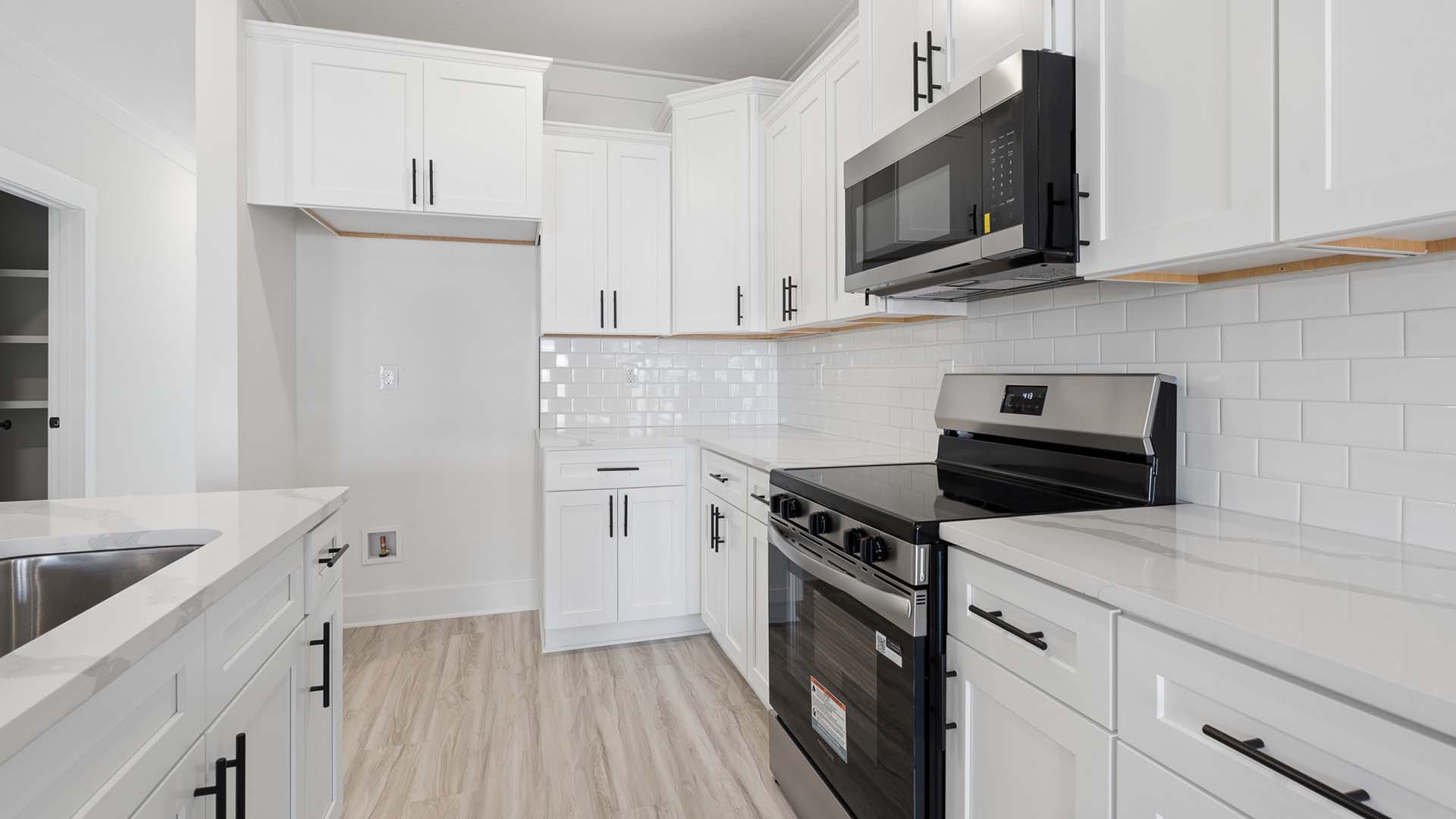 The beautiful white cabinetry is complemented by the quartz countertops and tile backsplash
