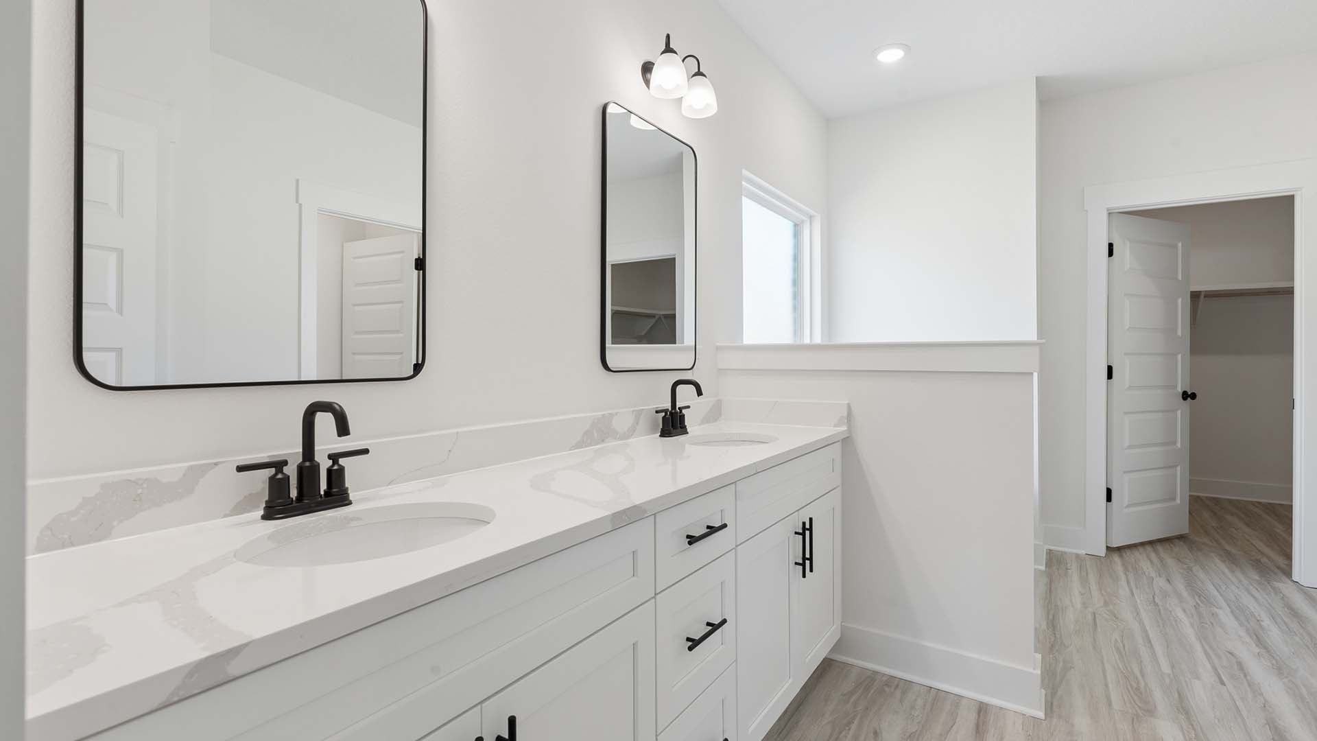 The primary bathroom has quartz countertops complemented by white cabinetry. The plumbing fixtures are matte lack