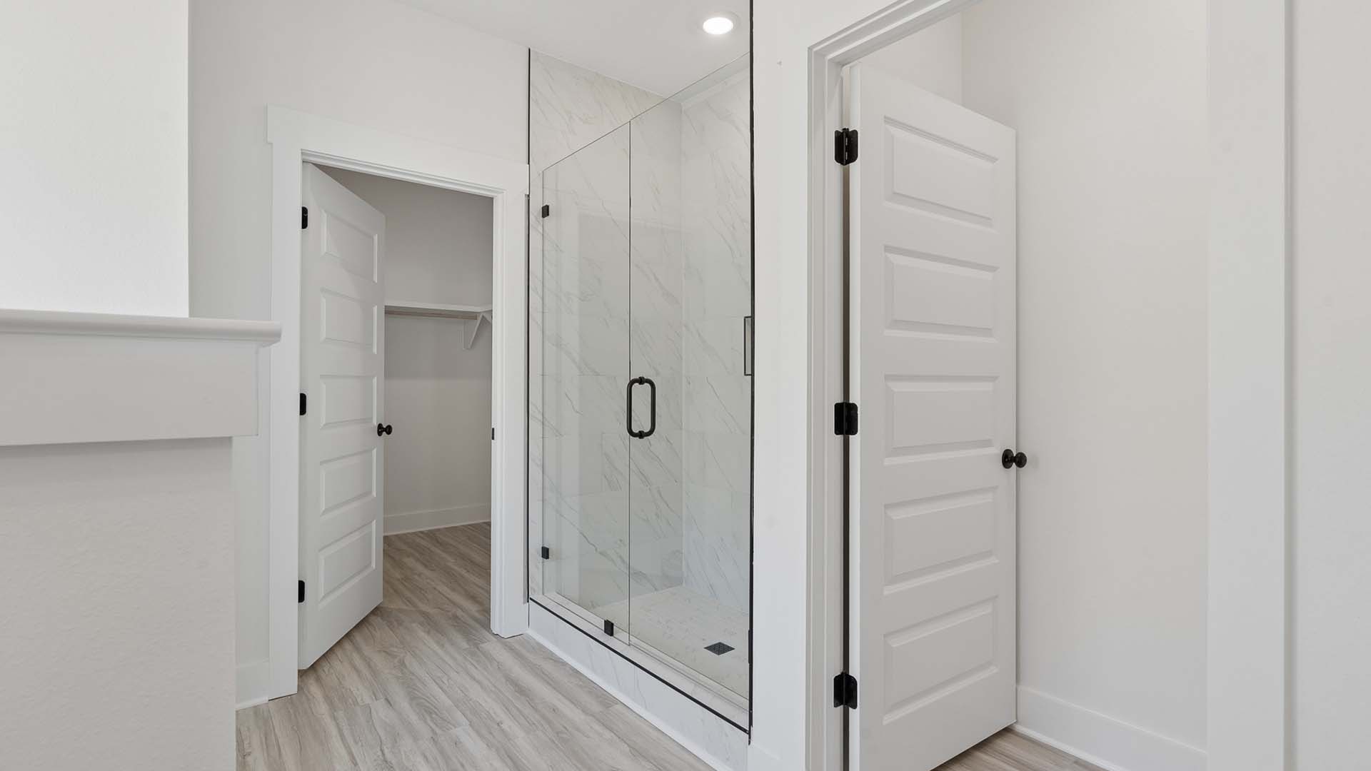 The primary bath has a shower with frameless glass enclosure