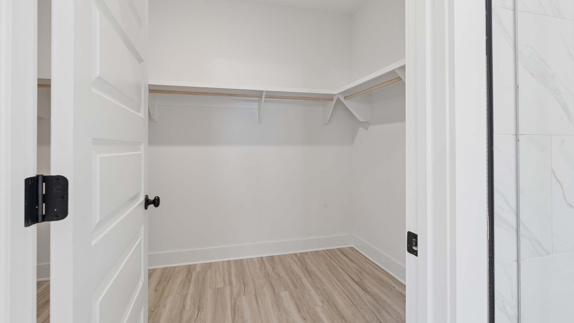The spacious closet in the primary bath has wood shelving