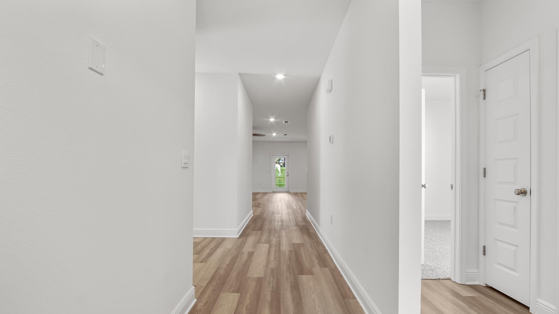 Foyer with EVP flooring and hallway to guest bedrooms and full bathroom and linen closet.