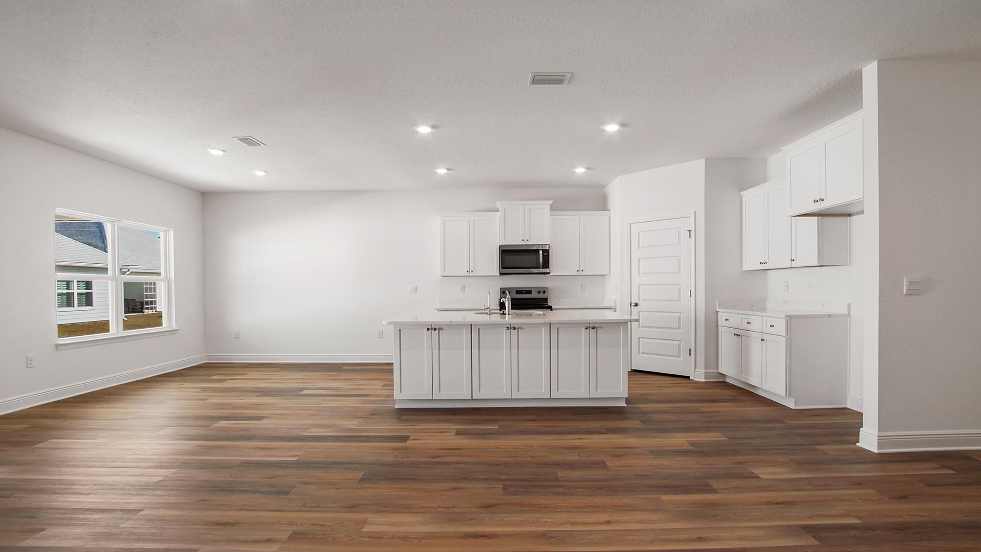 The kitchen has been elegantly appointed with white cabinetry and quartz countertops