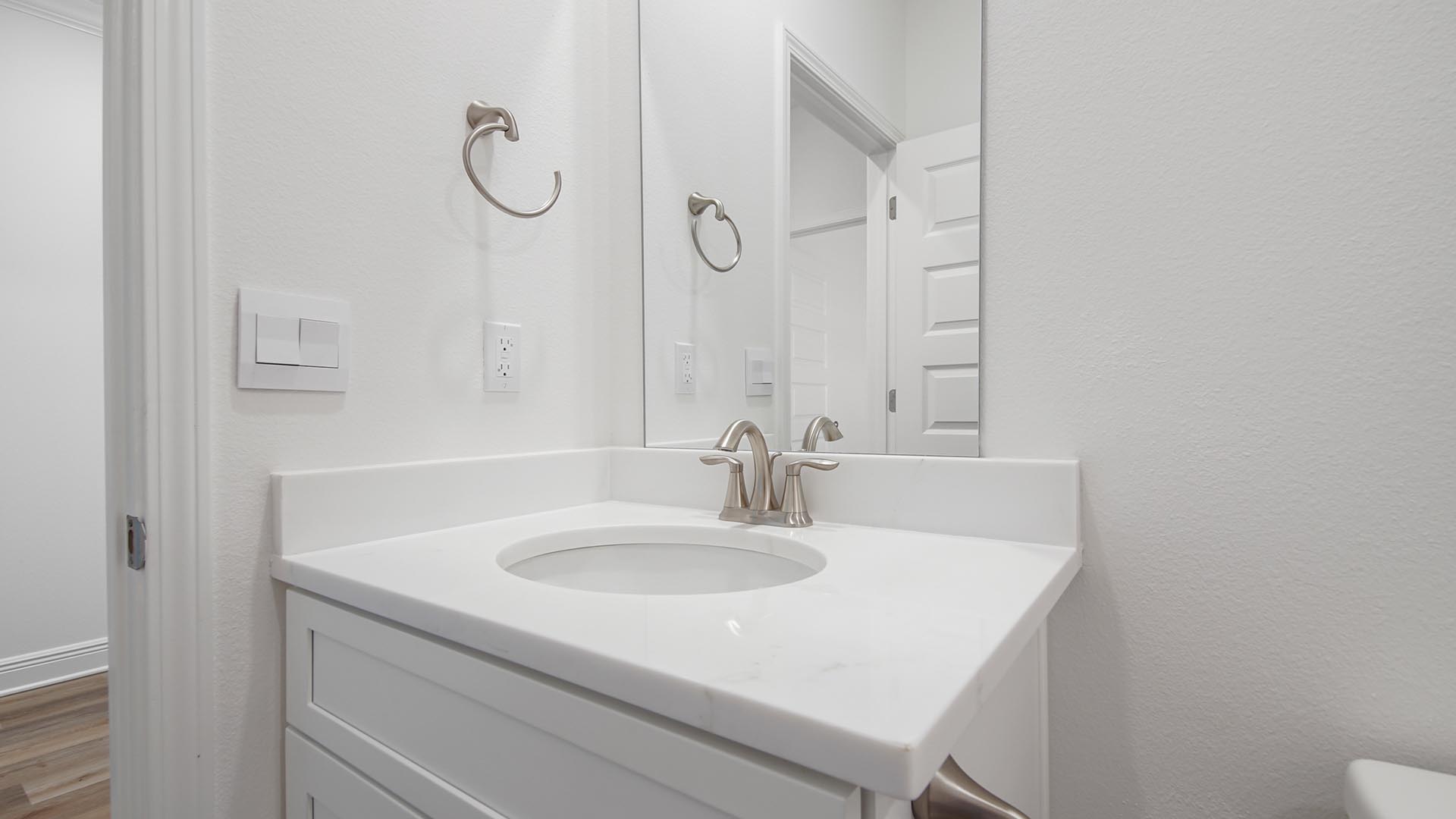 The single vanity in the shared bathroom features quartz countertops and lower cabinetry